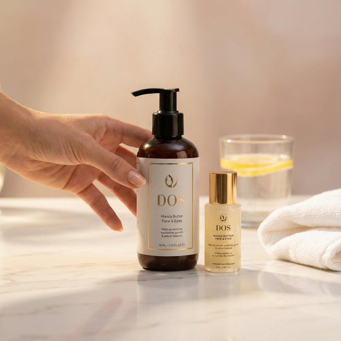 Hand holding Manca butter of DOS skincare product on a reflective surface with a glass and towel in the background in two sizes