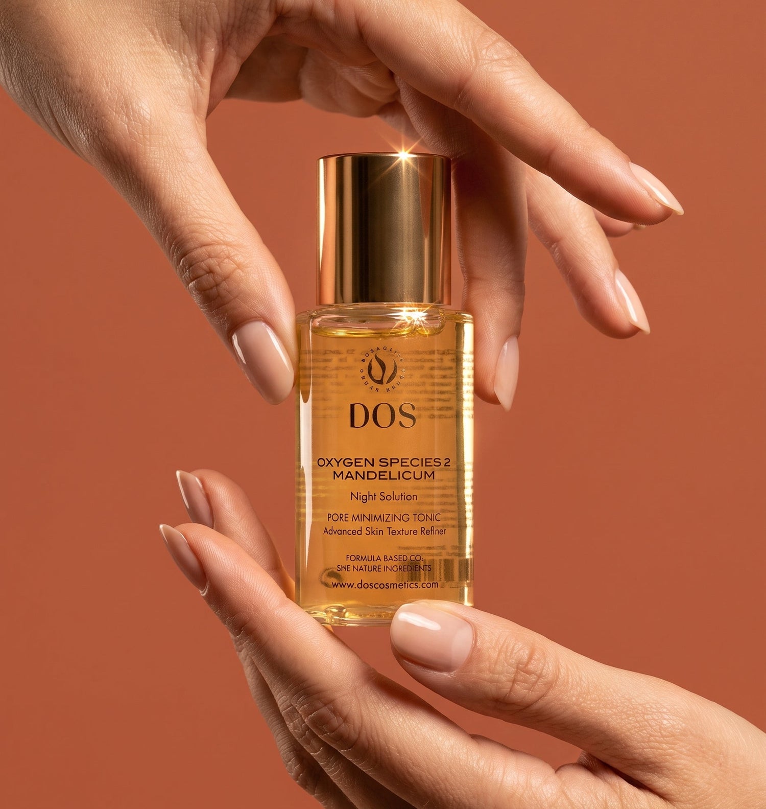 A bottle of DOS Oxygen Species Mandelicum night repair amine skin serum oil is held between two hands against a solid terracotta background. The product is a clear glass bottle filled with golden-yellow oil, topped with a metallic gold cap.