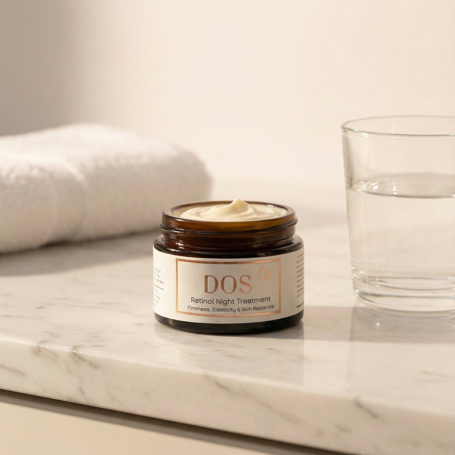 DOS Retinol night cream on a marble surface with a glass and towel in the background showing texture